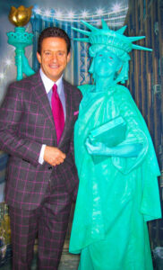 An actress is dressed and painted as the Statue of Liberty for an American Independence Day party and poses with man in a checkered suit.