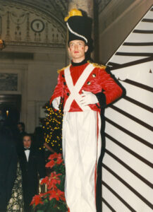An actor on stilts in a toy soldier costume for a Christmas party